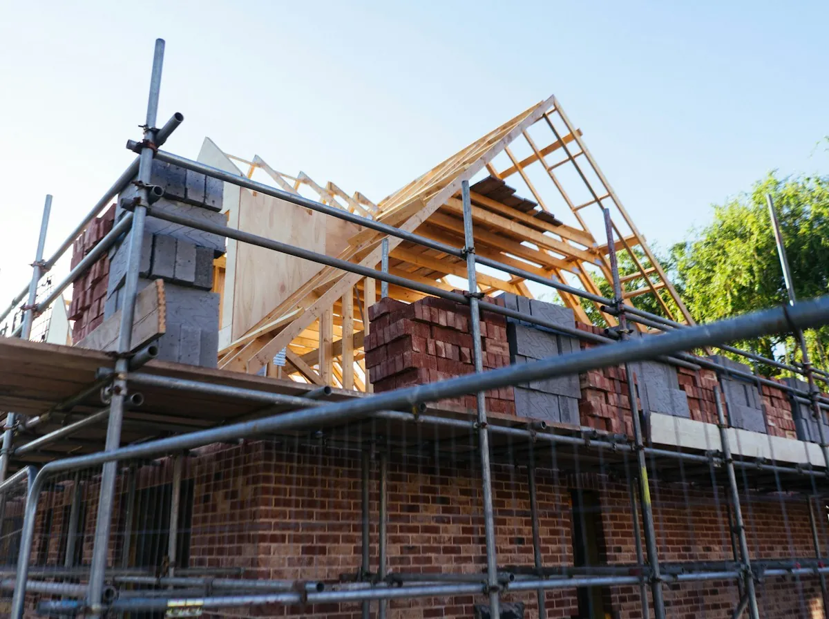 Roof Replacement in Elizabeth — roof framing going up on a brick house behind scaffolding
